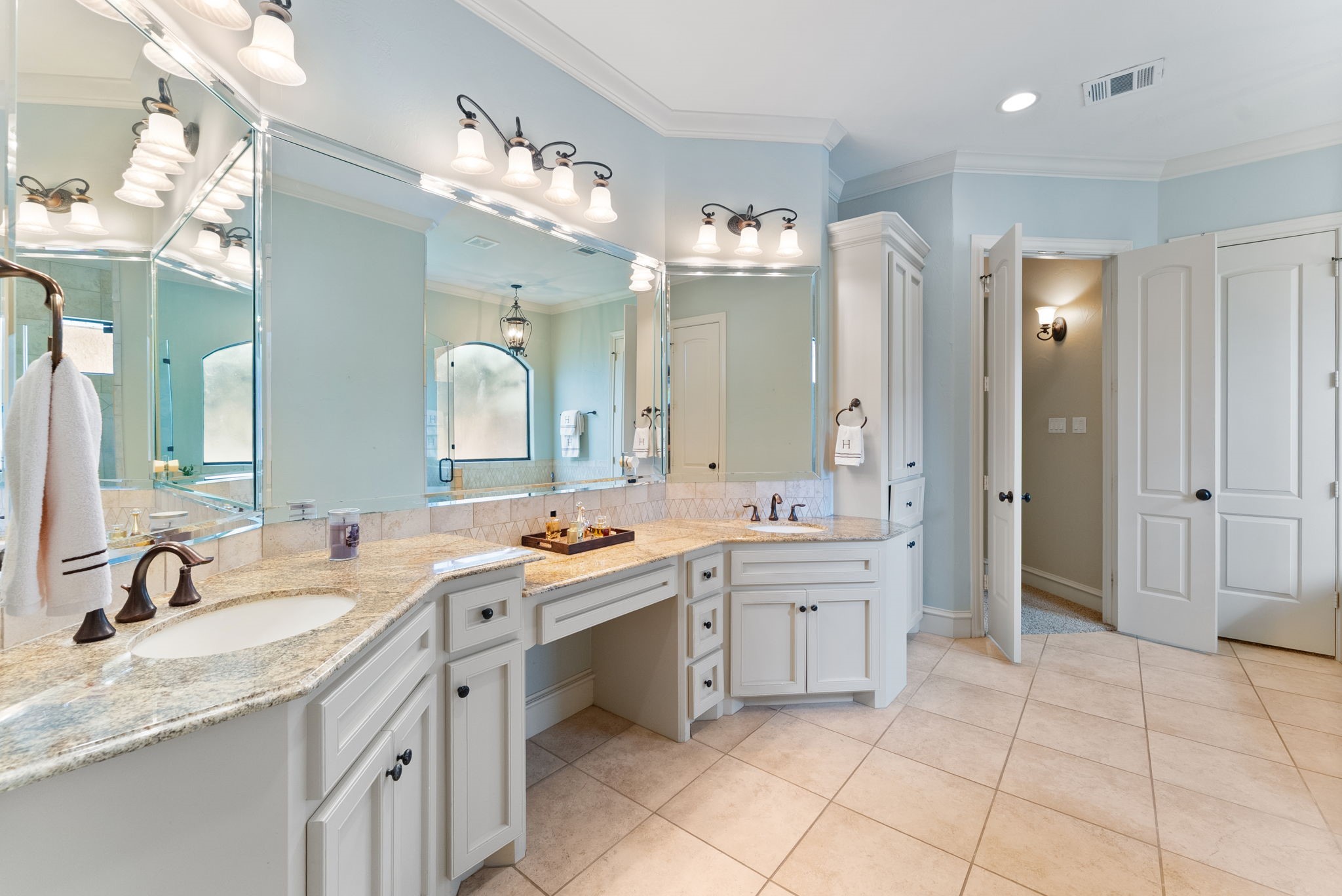 3907 Rayford Road Spring, TX 77386 - Photo 18 of 38 The Primary Bath offers an expansive vanity with dual sinks, granite countertops, a wraparound mirror, seated vanity space, and two built-in linen closets for added storage.