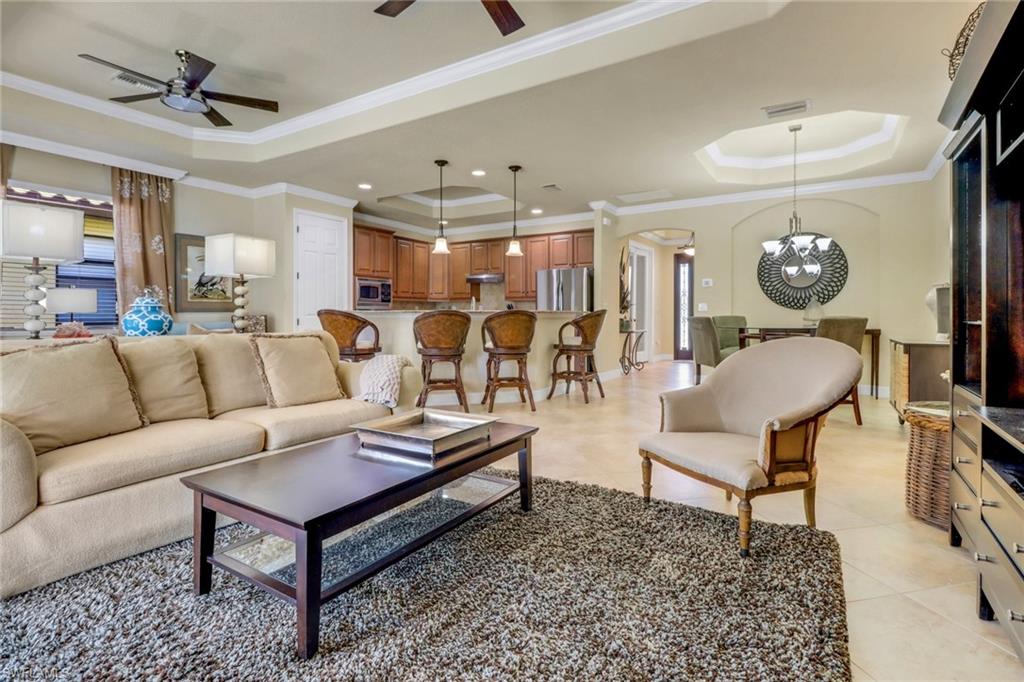 9434 Piacere Way Naples, FL 34113 - Photo 9 of 32 Living area with a tray ceiling, ceiling fan, arched walkways, ornamental molding, and light tile patterned floors
