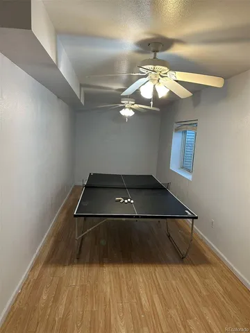 a room with a chandelier fan and wooden floor
