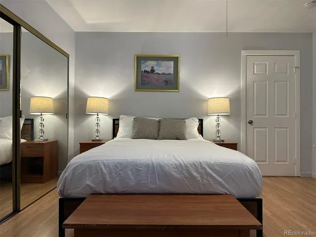 a bedroom with a bed a lamp and wooden floor