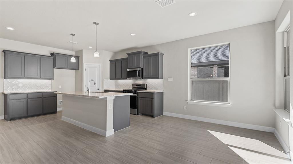 11305 Treehouse Trail Justin, TX 76247 - Photo 6 of 39 a large kitchen with a large counter top space a sink stainless steel appliances and cabinets