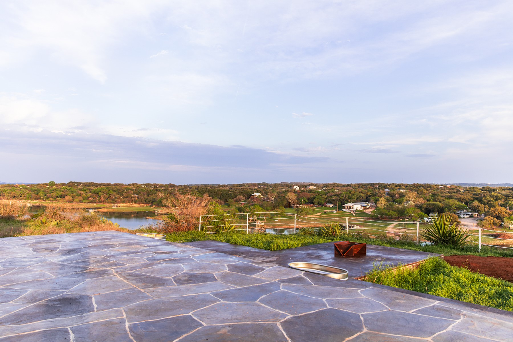 Natural flagstone paving frames a panoramic overlook of the tranquil water and rolling landscape.