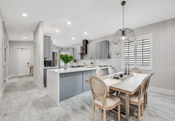 a kitchen with kitchen island a dining table chairs sink and cabinets