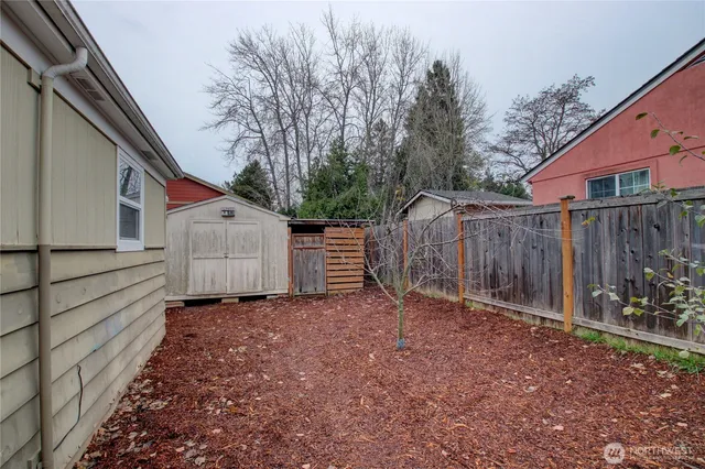 a view of backyard with wooden fence and a bench