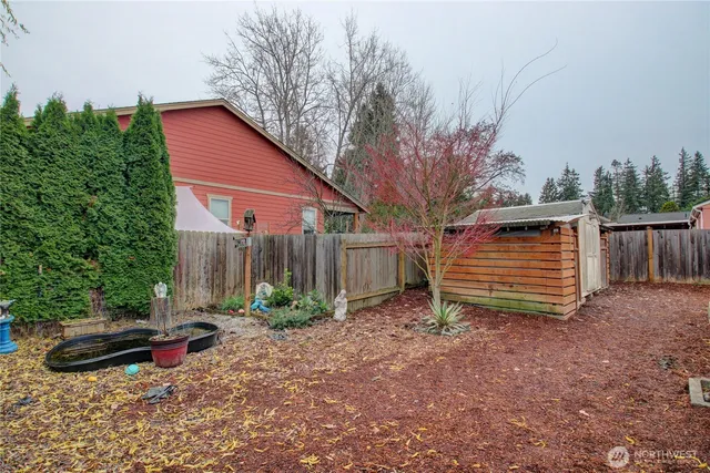 a view of backyard with large tree and wooden fence