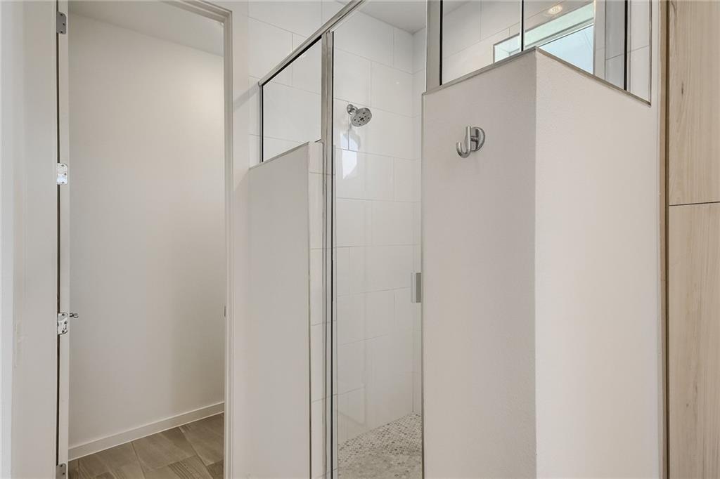 2624 Metcalfe Road, Unit 7 Austin, TX 78741 - Photo 17 of 31 Modern shower enclosure featuring a frameless glass door, white subway tile surround, and a rain showerhead