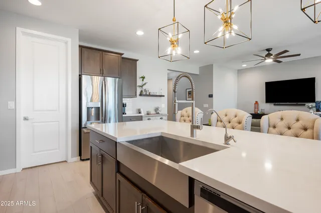 a kitchen with stainless steel appliances a sink a chandelier and living room view