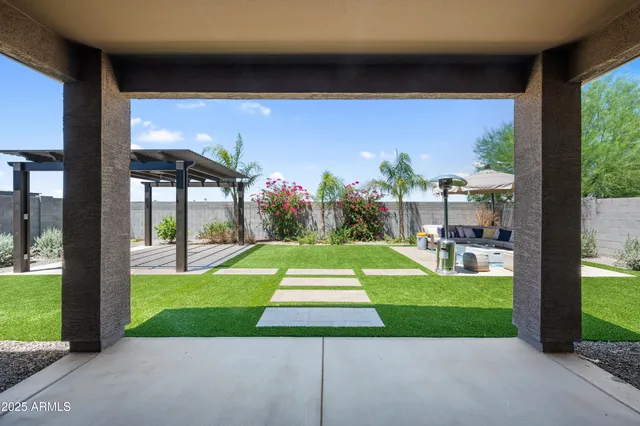 a view of a patio with couches and a table and chairs with plants and wooden fence