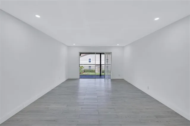 a view of an empty room with window and wooden floor