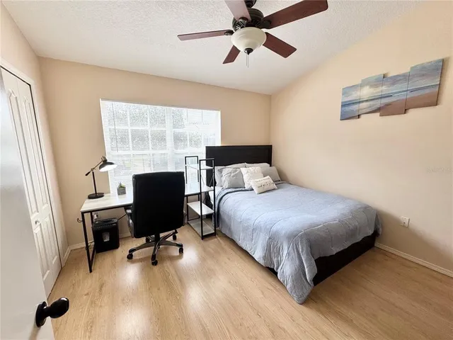 a bedroom with a bed a desk and chair with wooden floor