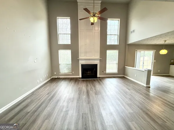 an empty room with wooden floor fireplace and windows
