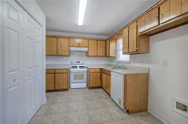a kitchen with a sink a stove cabinets and a window