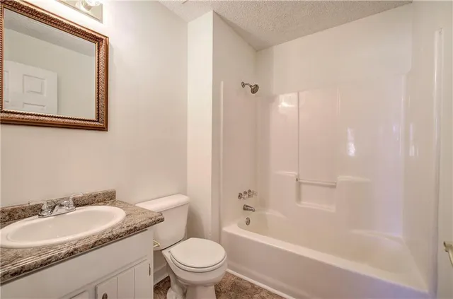 a bathroom with a granite countertop sink a toilet and a bathtub