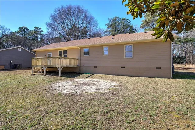 a backyard of a house with wooden fence and a tree