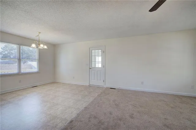an empty room with windows and chandelier fan