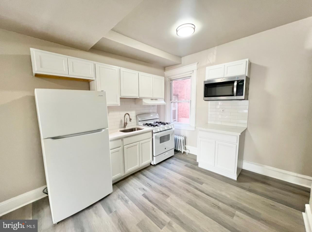 1607 South 60th Street, Unit 1 Philadelphia, PA 19142 - Photo 8 of 16 a kitchen with white cabinets and white appliances