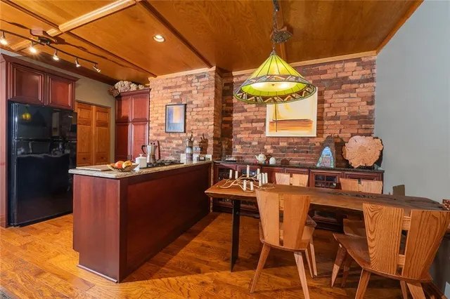 a dining room with stainless steel appliances kitchen island granite countertop a table chairs in it and a window