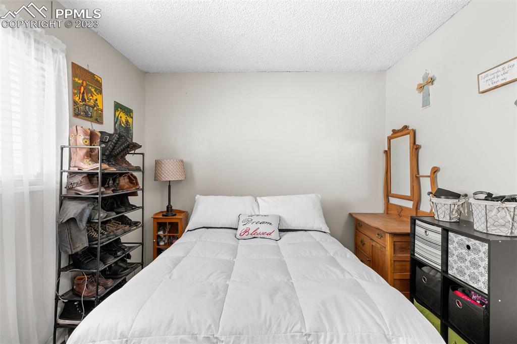 125 Chelton Road Colorado Springs, CO 80909 - Photo 11 of 26 a bedroom with a bed and a flat tv screen