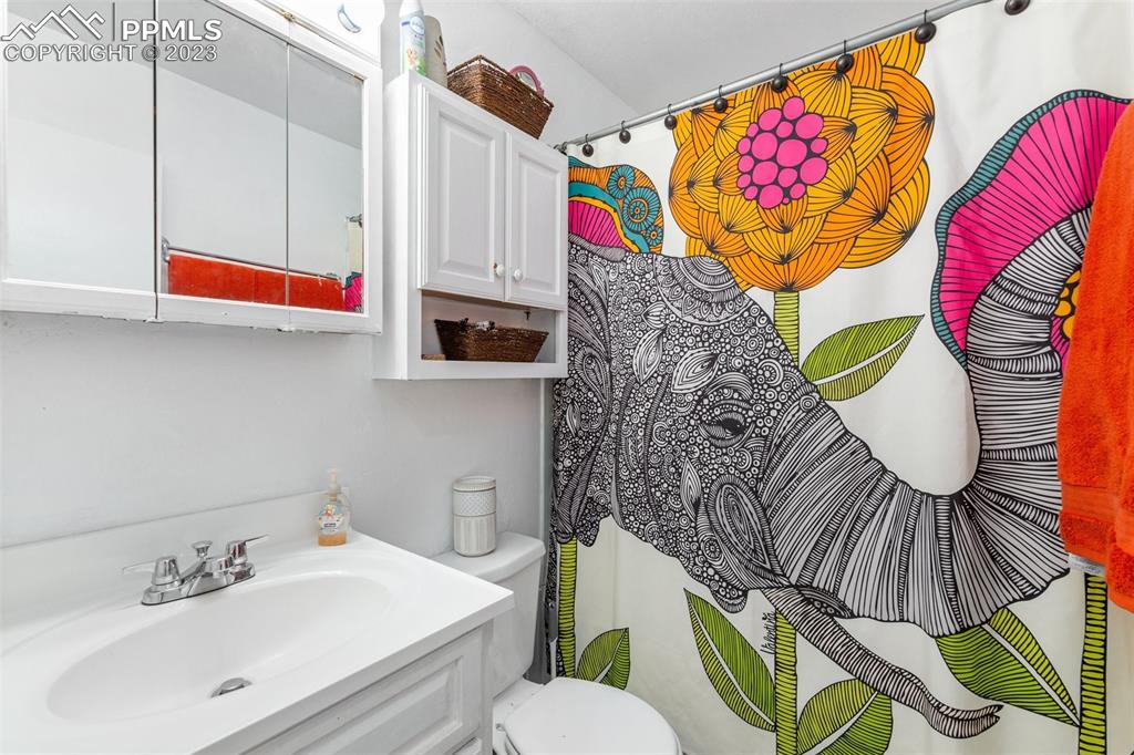 125 Chelton Road Colorado Springs, CO 80909 - Photo 12 of 26 a bathroom with a sink a mirror and painting on the wall