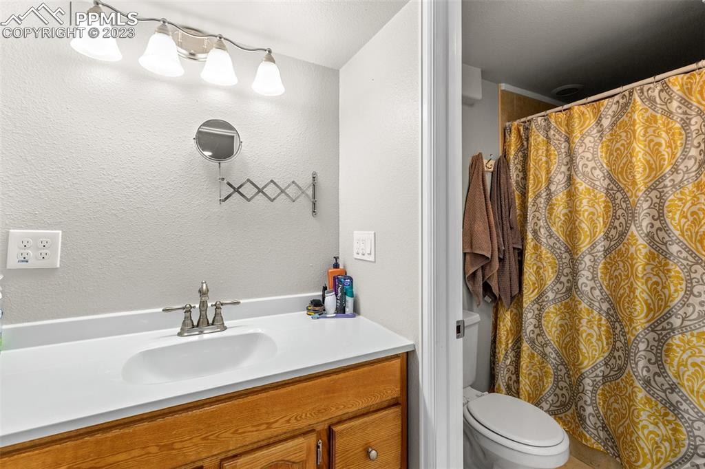 125 Chelton Road Colorado Springs, CO 80909 - Photo 19 of 26 a bathroom with a sink vanity mirror and toilet