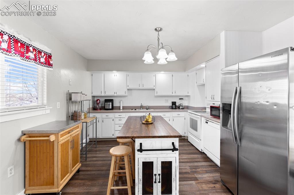 125 Chelton Road Colorado Springs, CO 80909 - Photo 8 of 26 a kitchen with a refrigerator a sink dishwasher a stove and white cabinets with wooden floor