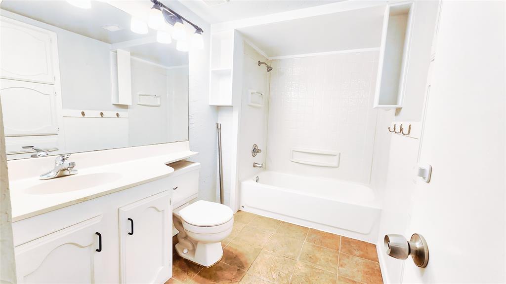 3905 Windflower Lane Fort Worth, TX 76137 - Photo 19 of 32 a bathroom with a granite countertop sink toilet a shower and a mirror