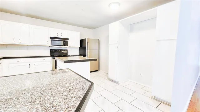 a kitchen with granite countertop a refrigerator and cabinets