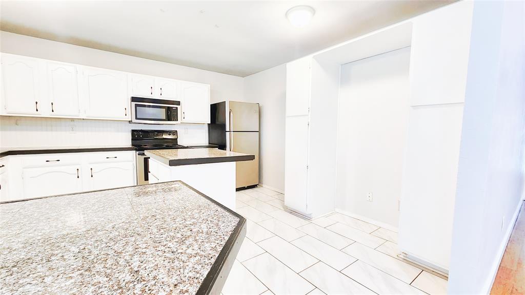 3905 Windflower Lane Fort Worth, TX 76137 - Photo 8 of 32 a kitchen with granite countertop a refrigerator and cabinets