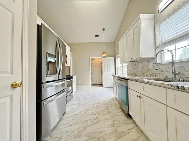 a kitchen with granite countertop a refrigerator and a sink