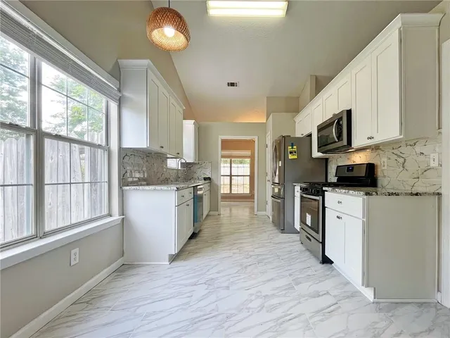 a kitchen with stainless steel appliances granite countertop a stove a sink and a refrigerator