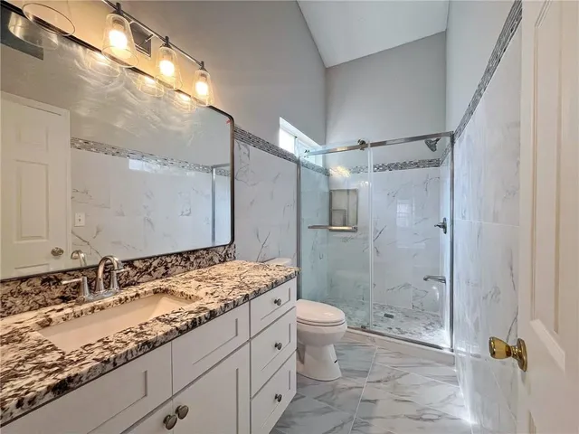 a bathroom with a granite countertop sink toilet and shower