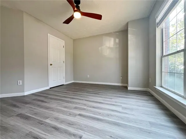 a view of an empty room with wooden floor and a window