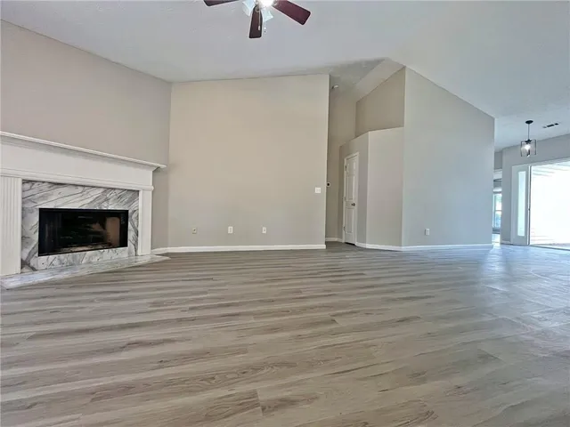 an empty room with wooden floor fireplace and windows