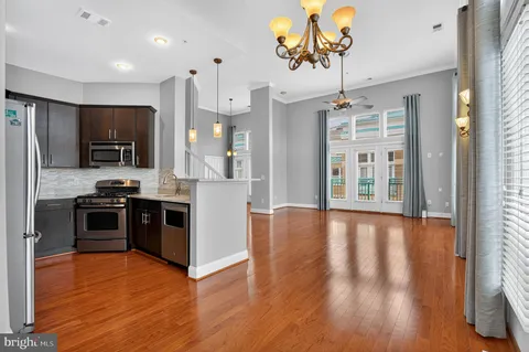 a kitchen with stainless steel appliances granite countertop a refrigerator a stove top oven a sink dishwasher and wooden floor