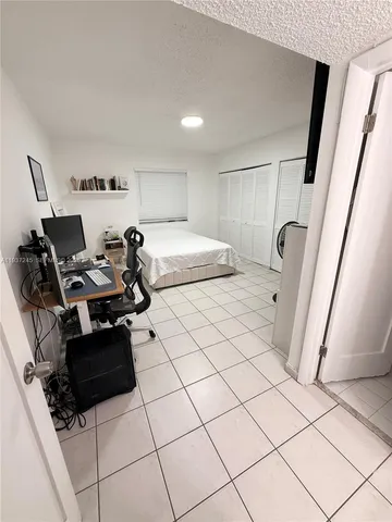 a bedroom with a bed and a refrigerator