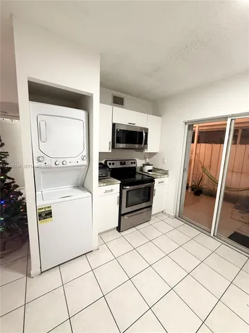 a kitchen with white cabinets and appliances