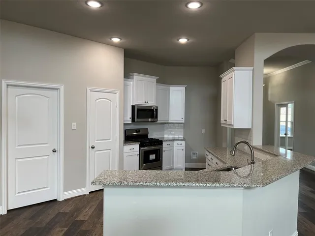 a kitchen with granite countertop white cabinets and stainless steel appliances