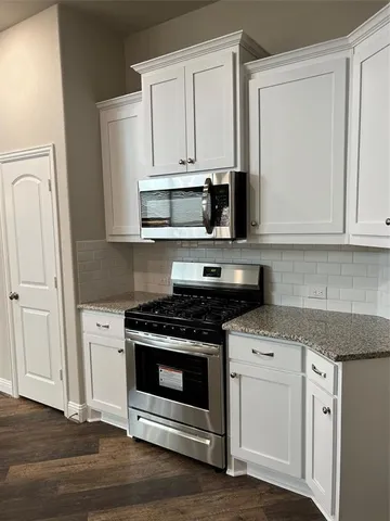 a kitchen with stainless steel appliances granite countertop a stove a sink and white cabinets