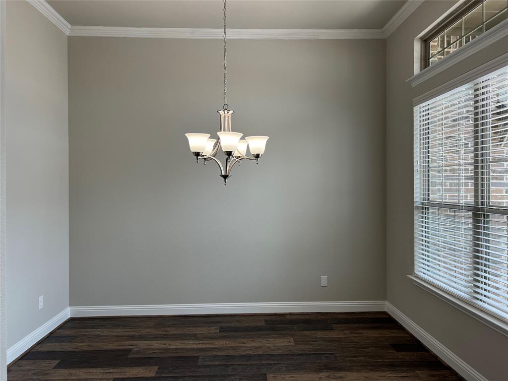 277 Eagle Ridge Forney, TX 75126 - Photo 8 of 19 Empty room featuring dark wood-style flooring, crown molding, and a chandelier