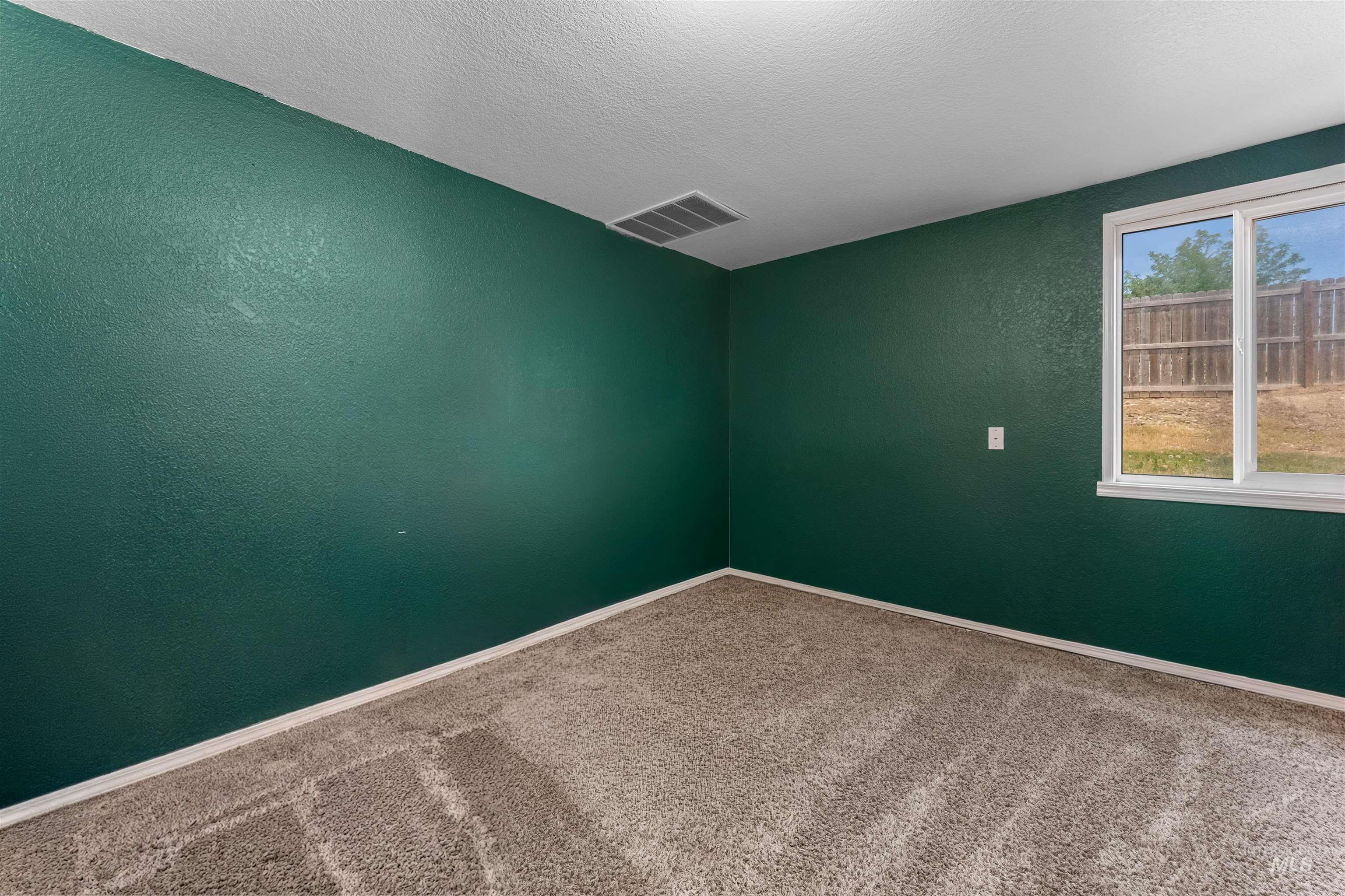 17441 Upper Pleasant Ridge Road Caldwell, ID 83607 - Photo 20 of 40 Carpeted room featuring a single-pane window with white trim, dark green walls, white baseboards, and a ceiling-mounted HVAC vent