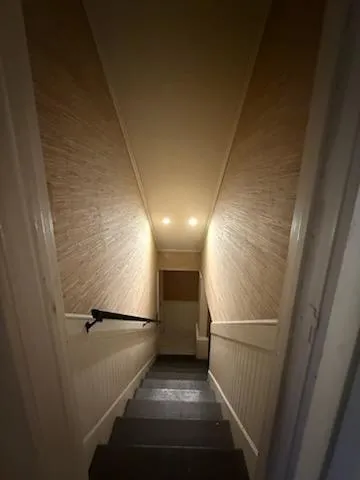 a view of a refrigerator in kitchen and an empty room