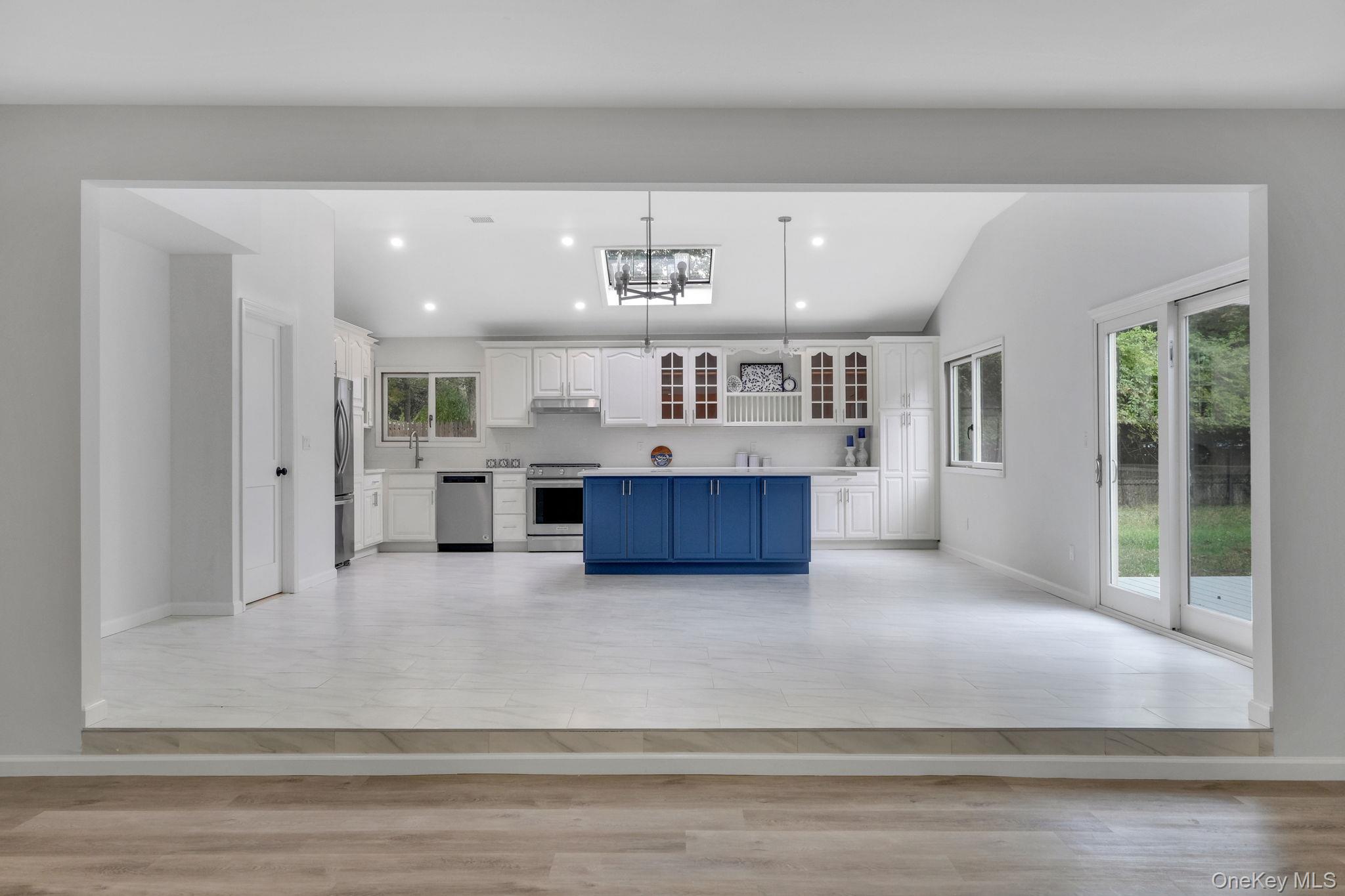 11 Wildwood Road Ridge, NY 11961 - Photo 17 of 17 Kitchen featuring white cabinets, glass insert cabinets, open floor plan, pendant lighting, and light countertops