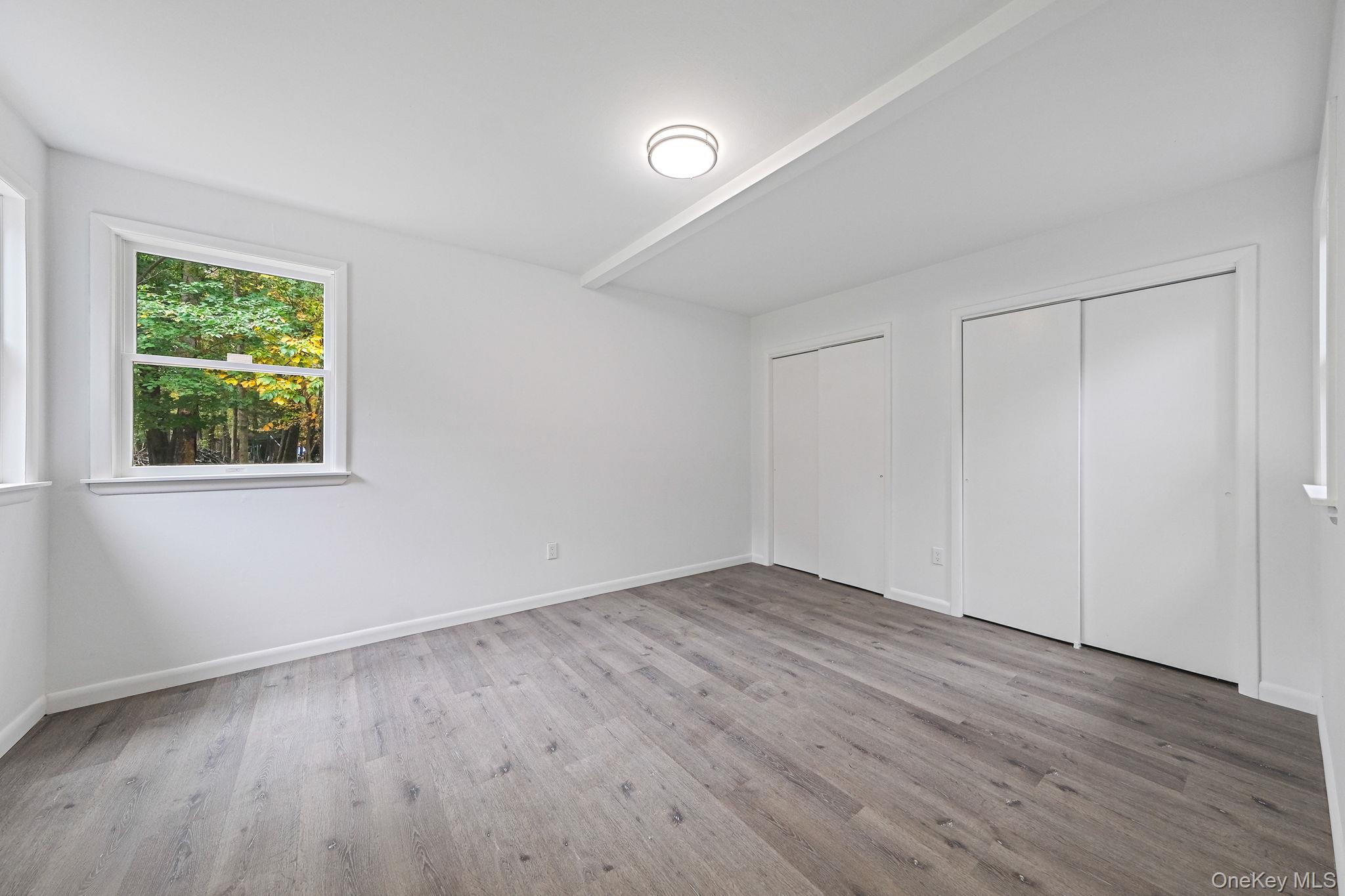 11 Wildwood Road Ridge, NY 11961 - Photo 10 of 17 Unfurnished bedroom with multiple closets, light wood finished floors, and beam ceiling