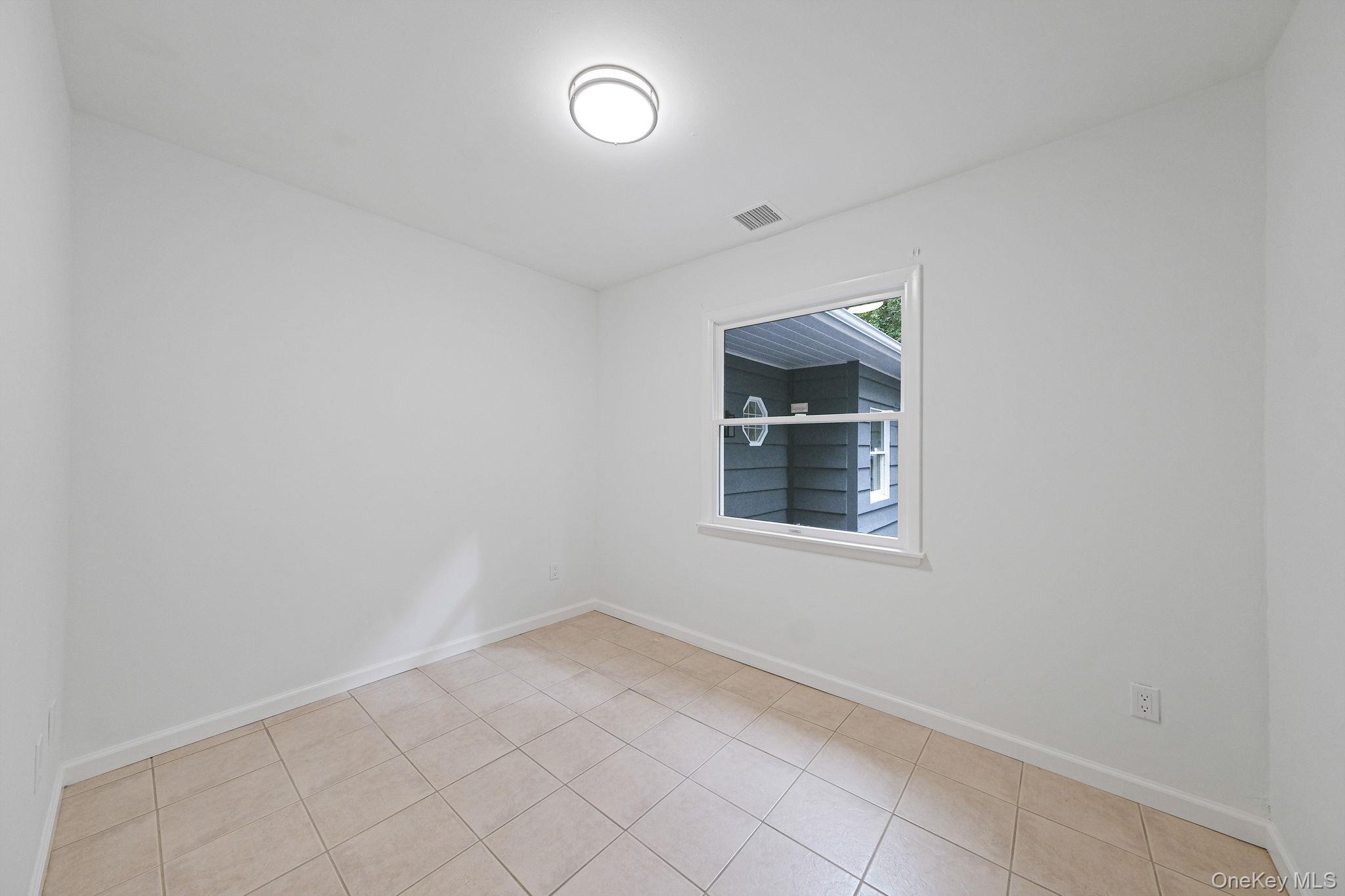 11 Wildwood Road Ridge, NY 11961 - Photo 13 of 17 Unfurnished room featuring baseboards and light tile patterned floors