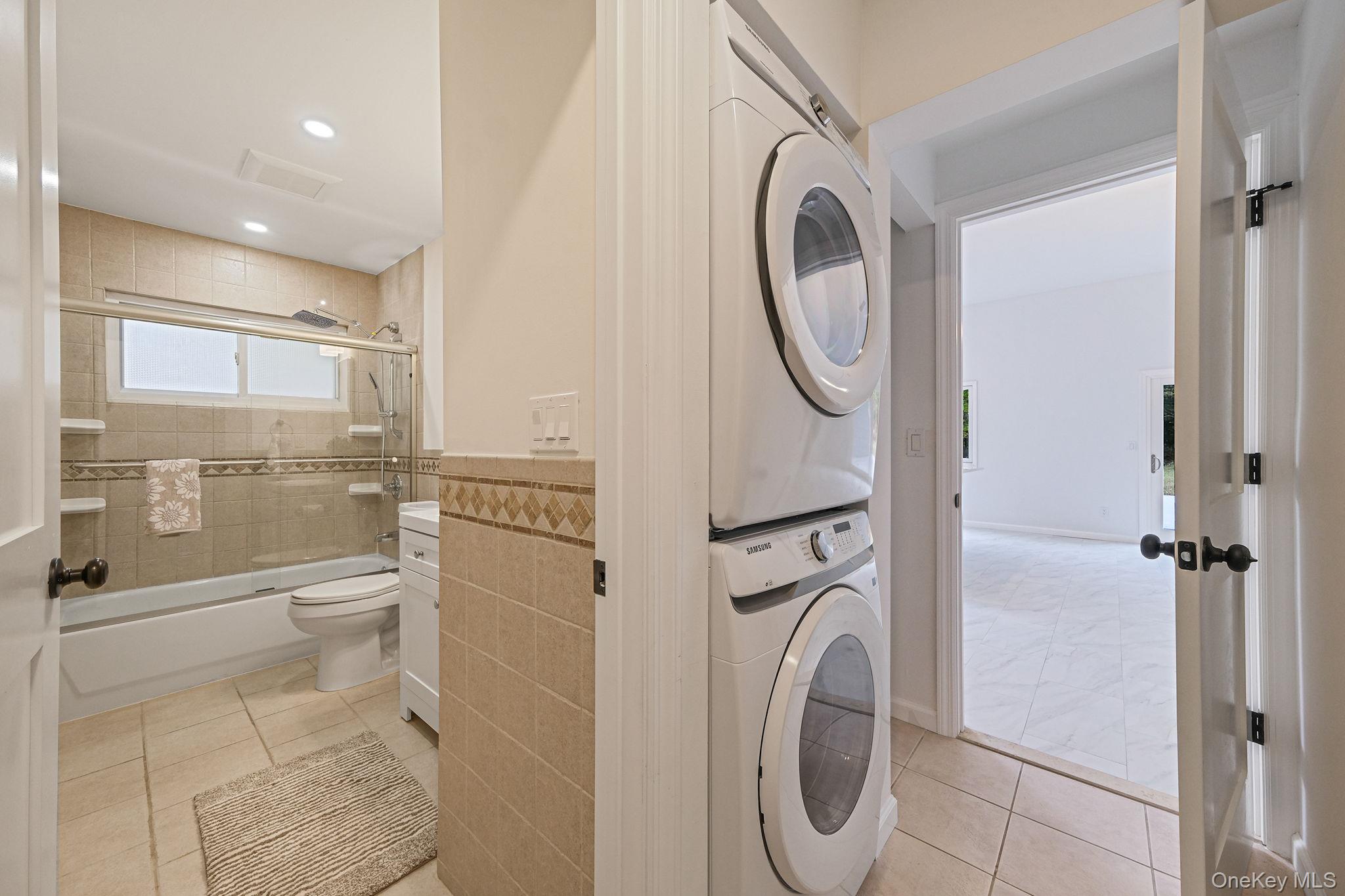 11 Wildwood Road Ridge, NY 11961 - Photo 16 of 17 Washroom with recessed lighting, estacked washer and dryer, tile walls, light tile patterned flooring, and wainscoting