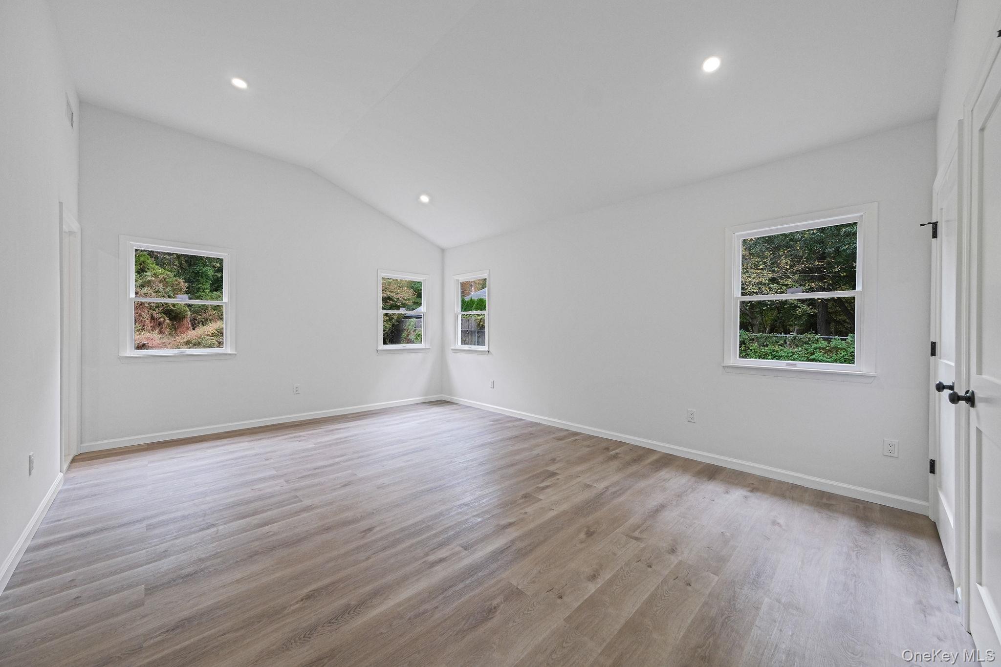 11 Wildwood Road Ridge, NY 11961 - Photo 7 of 17 Unfurnished room featuring healthy amount of natural light, lofted ceiling, recessed lighting, and light wood-style flooring