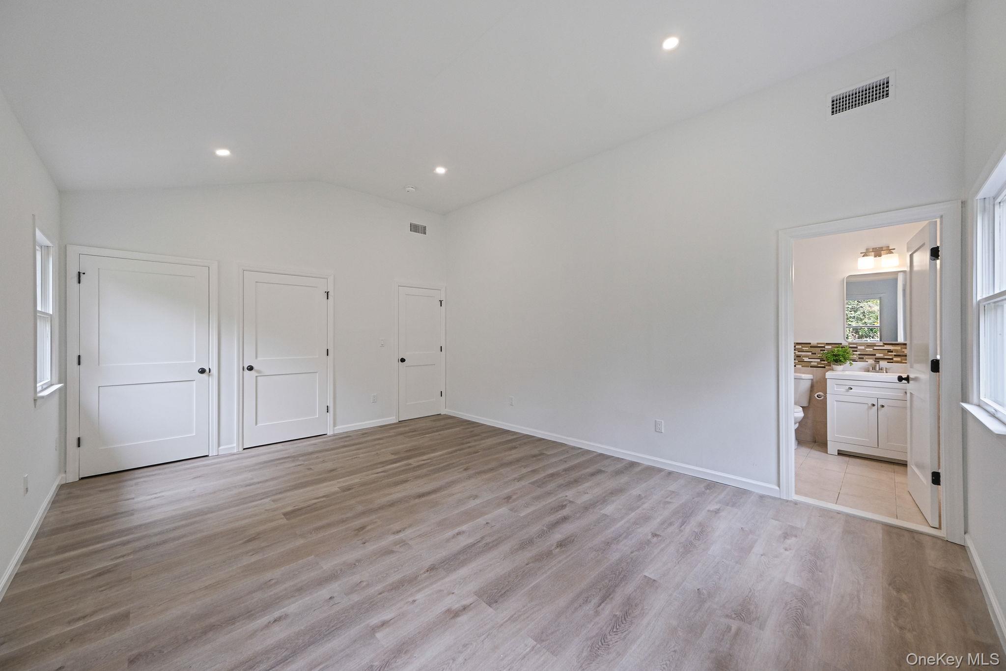 11 Wildwood Road Ridge, NY 11961 - Photo 8 of 17 Unfurnished bedroom featuring multiple windows, vaulted ceiling, light wood finished floors, recessed lighting, and ensuite bathroom