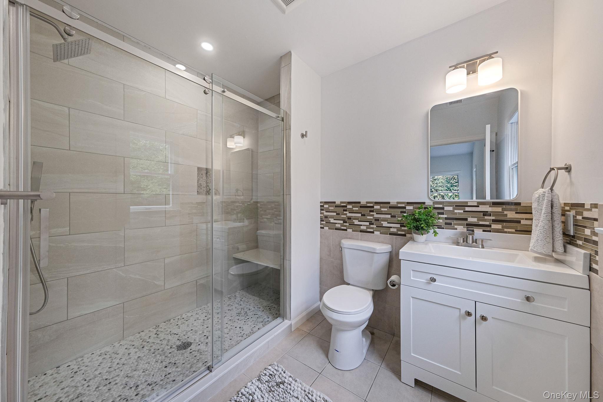 11 Wildwood Road Ridge, NY 11961 - Photo 9 of 17 Bathroom featuring vanity, a stall shower, tile walls, light tile patterned flooring, and healthy amount of natural light