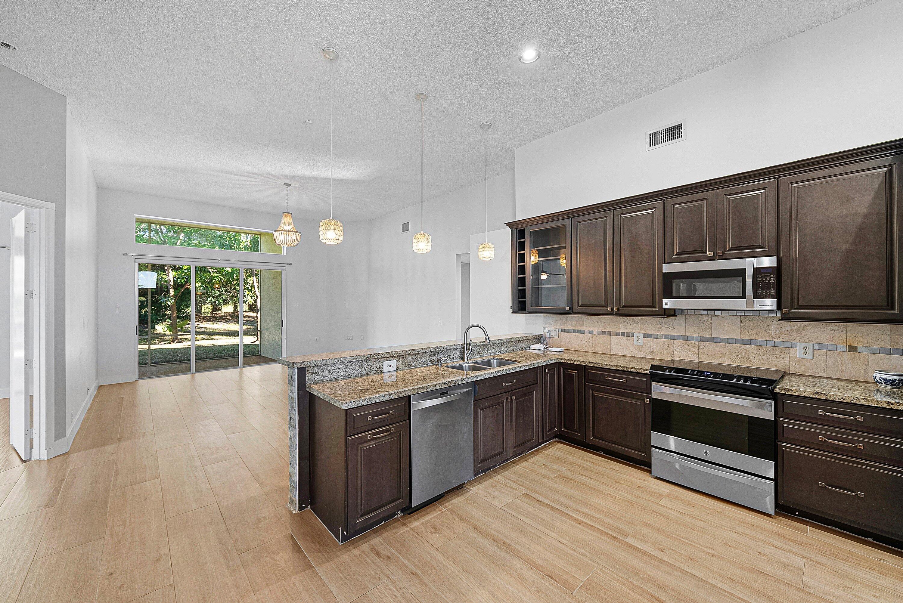 19712 Dinner Key Drive Boca Raton, FL 33498 - Photo 13 of 28 a kitchen with stainless steel appliances granite countertop wooden cabinets a sink dishwasher a stove and a refrigerator with wooden floor