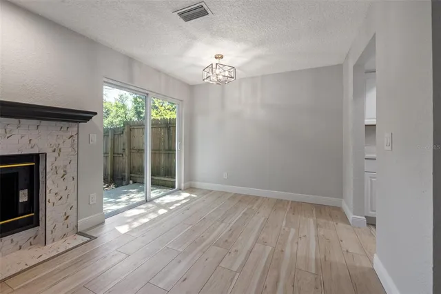 a view of an empty room with wooden floor and a chandelier fan